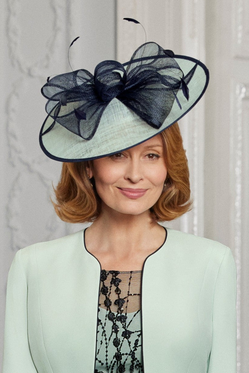 Woman wearing a stylish hat with a large bow against a neutral background