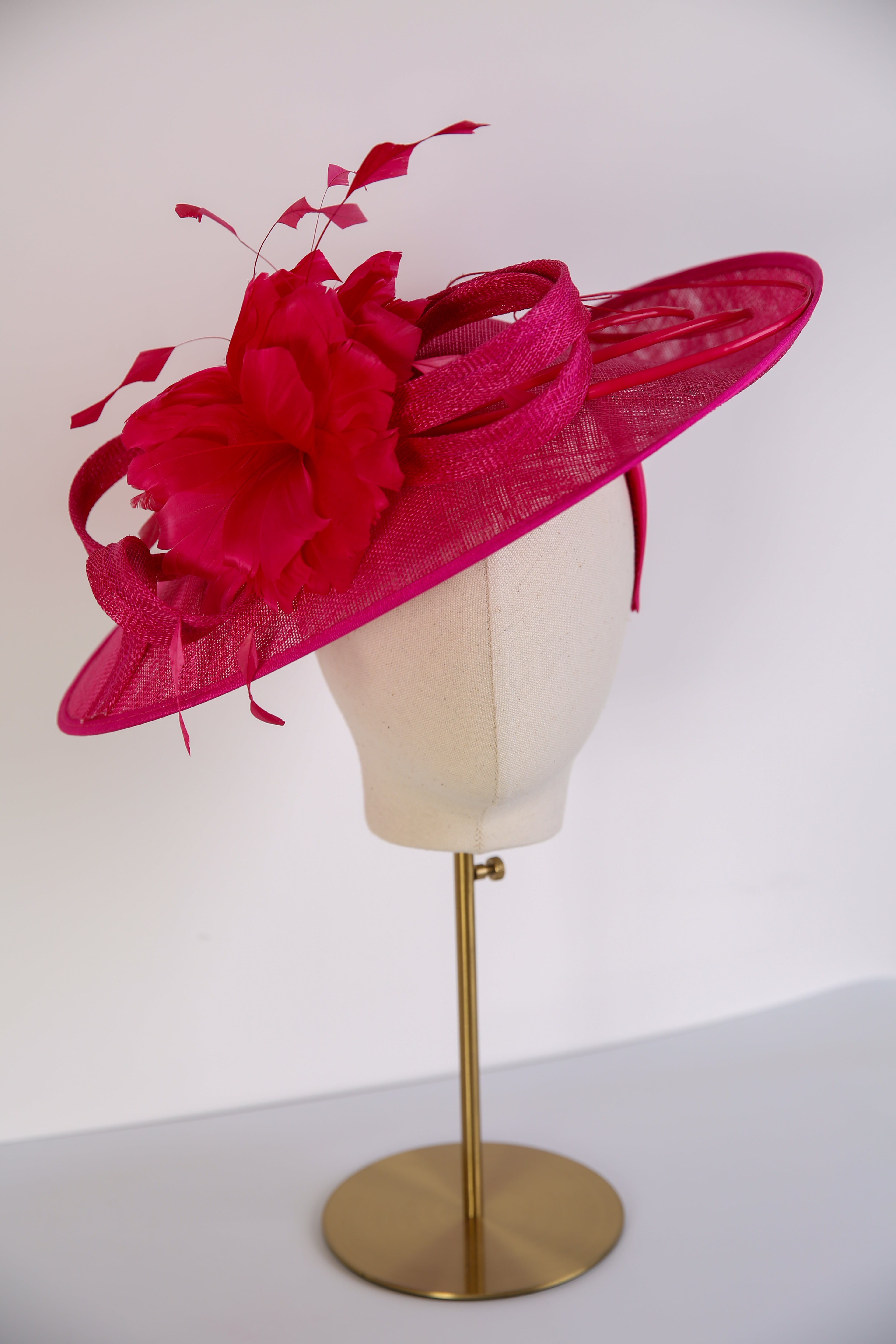 Fuchsia pink hat with floral details on a mannequin head against a white background