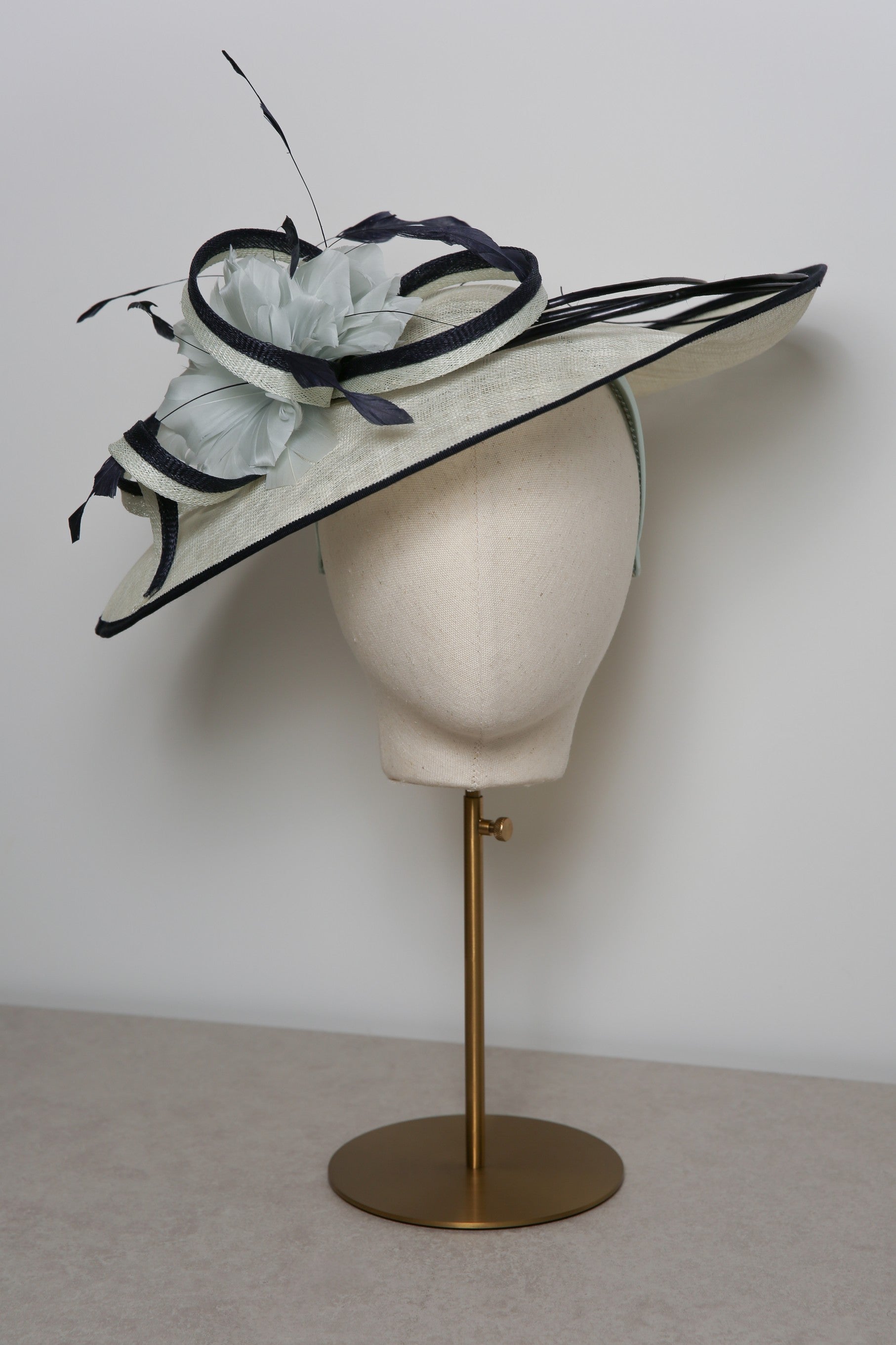 Mint and navy decorative hat on a mannequin head against a plain background