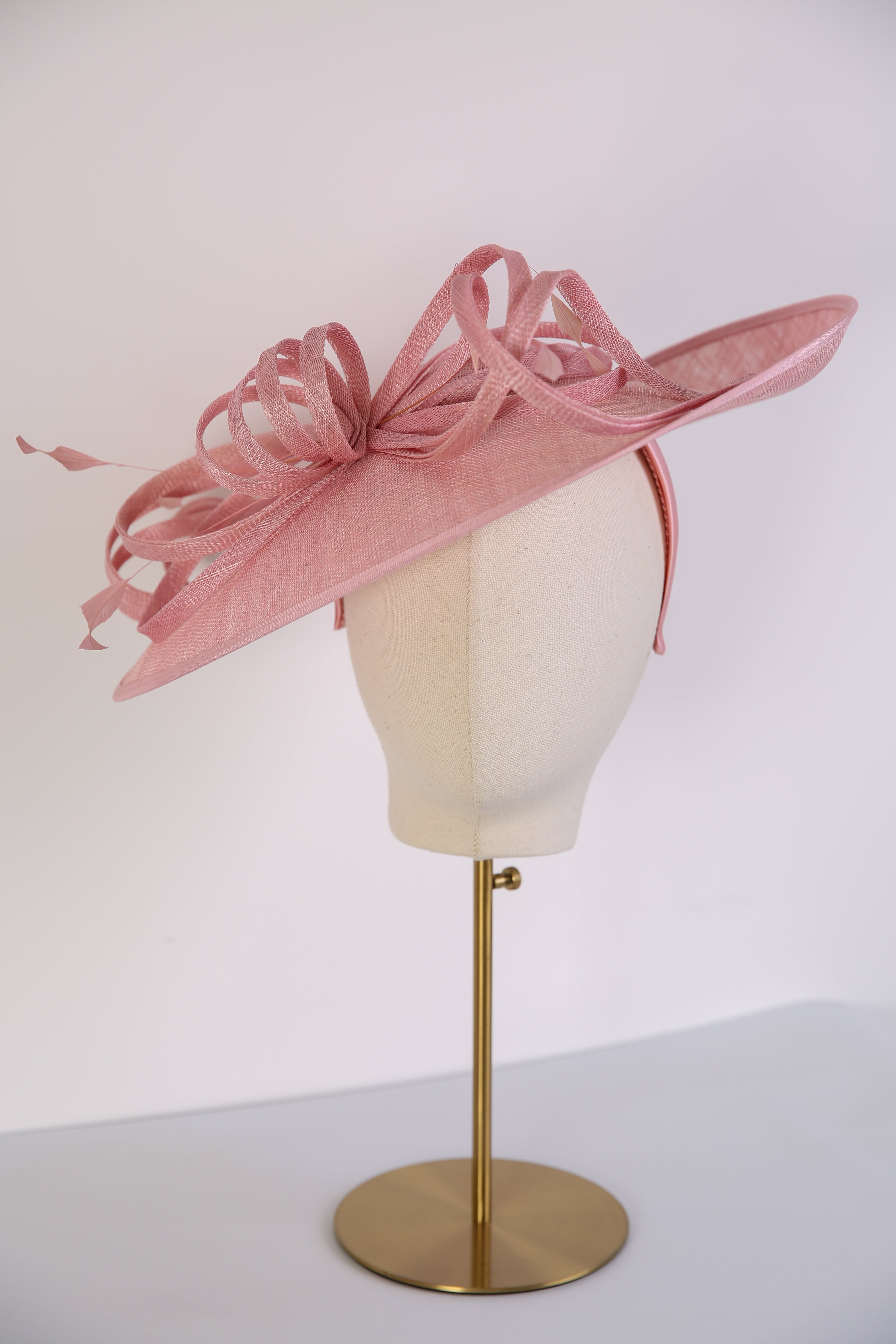 Pink decorative hat on a mannequin head against a white background