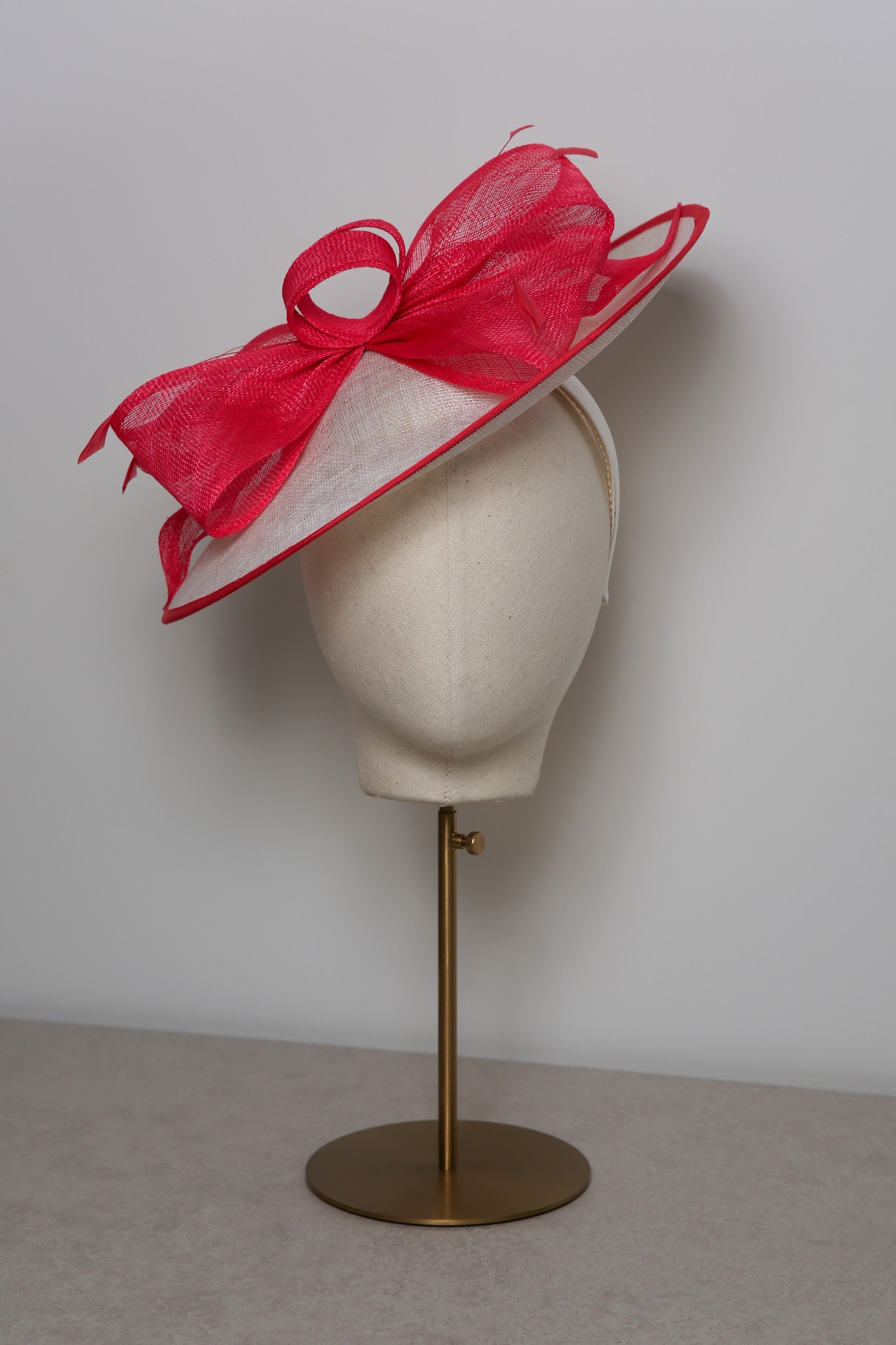 Pink and white hat on a mannequin head against a plain background