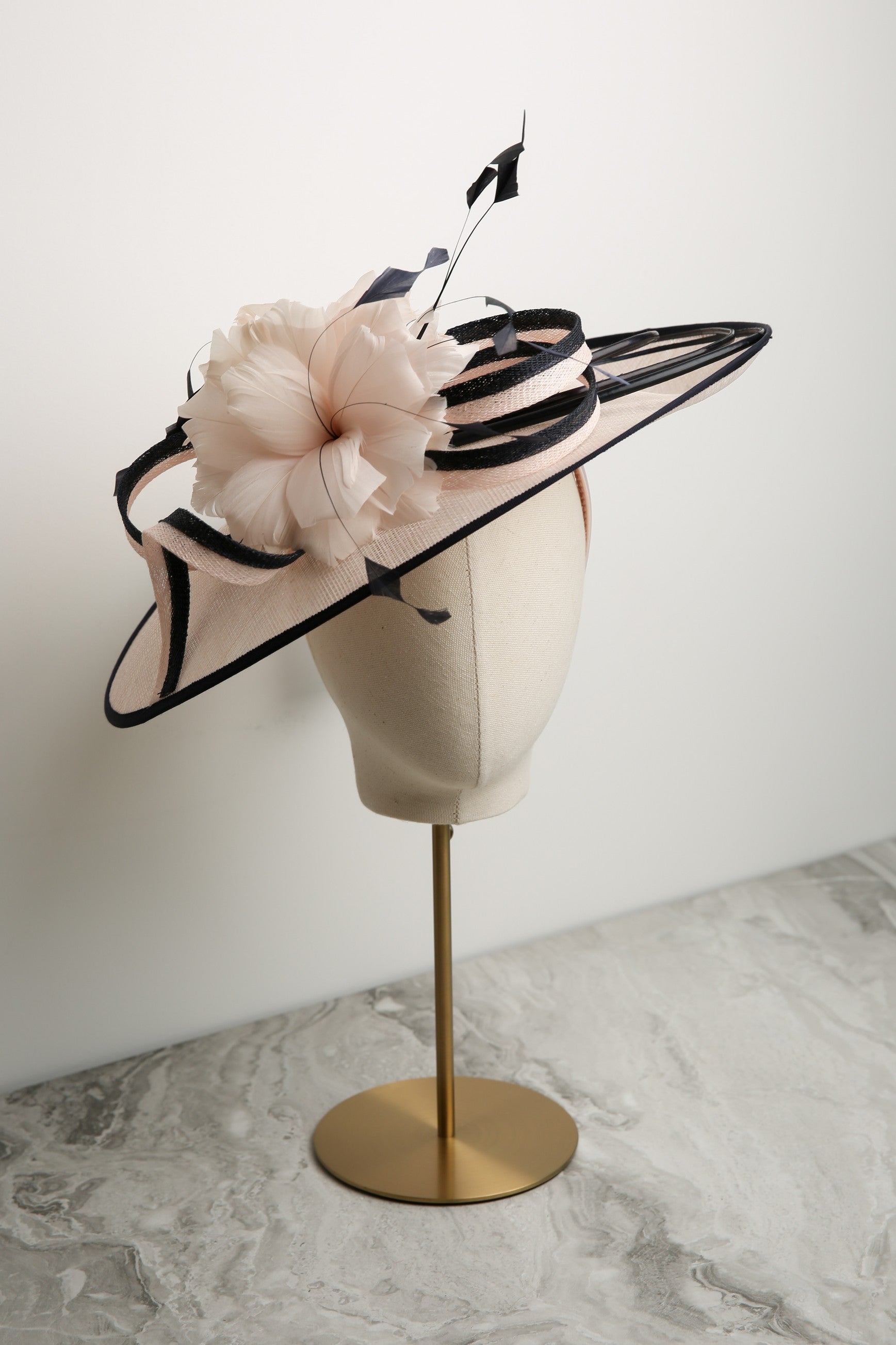 Pink and navy decorative hat on a mannequin head against a white background